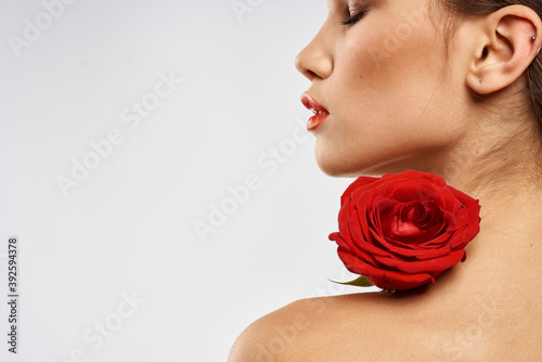 Portrait of woman with red rose naked shoulders Make-up on brunette face