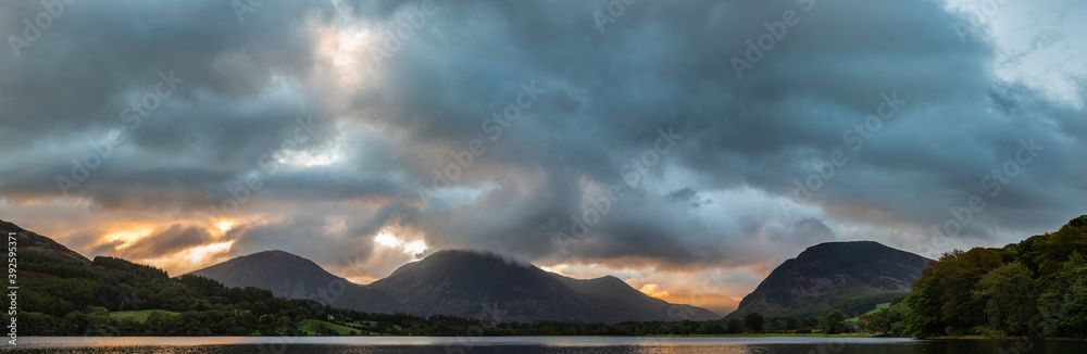 Beautiful sunrise landscape image looking across Loweswater in the Lake District towards Low Fell and Grasmere with vibrant sunrise sky breaking on the mountain peaks Beautiful sunrise landscape image looking across Loweswater in the Lake District towards Low Fell and Grasmere with vibrant sunrise sky breaking on the mountain peaks