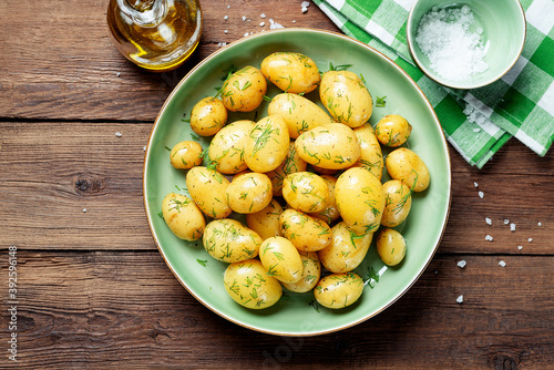 Schilderij op canvas Fresh boiled new potatoes with fresh dill on wooden background