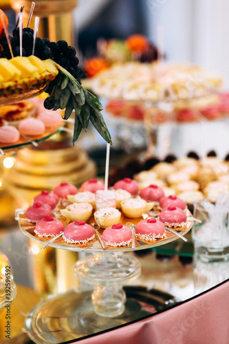Festive candy bar with cake  macaroons  desserts and fruit decorated with flowers on a round table