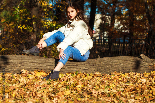 Young beautiful brunette girl in blue jeans, autumn park outdoor