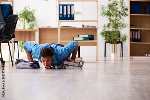 Young male employee doing sport exercises at workplace © Elnur