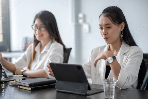Two young asian businesswoman discussing new business projects during at office meeting.
