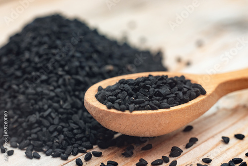 Black cumin seeds on wooden spoon on wooden background