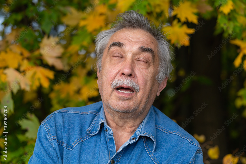 Portrait of a 70-year old elderly man who closed his eyes, but he barely suppresses laughter. Portrait of a 70-year old elderly man who closed his eyes, but he barely suppresses laughter.