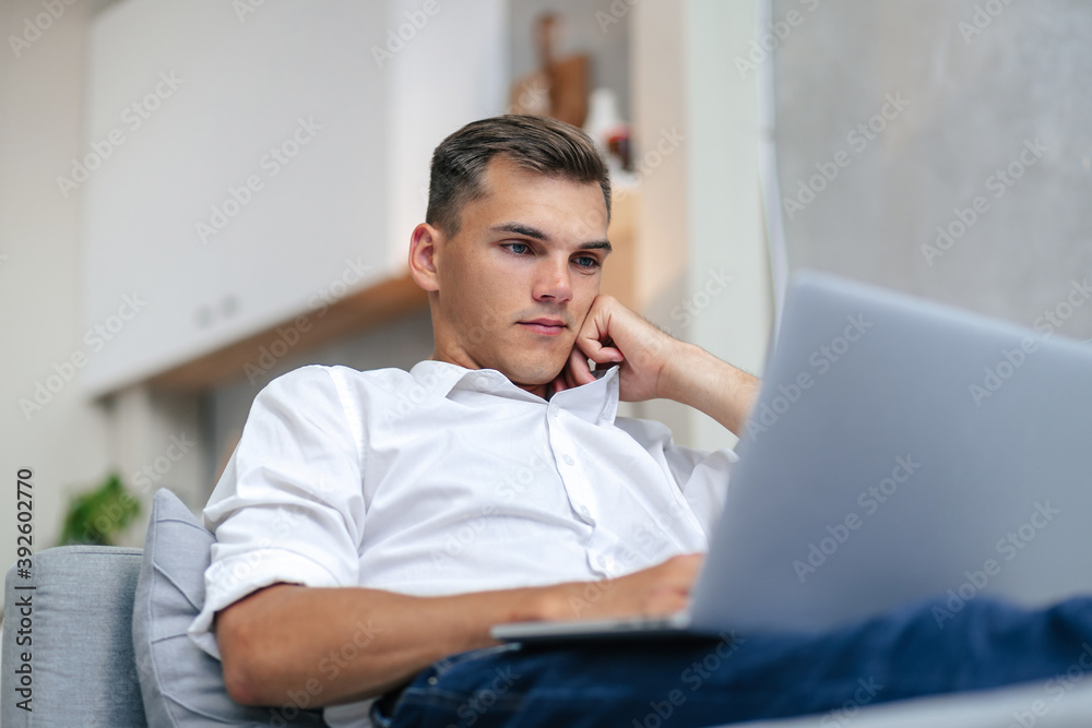 thoughtful young man browsing the Internet while lying on the couch. thoughtful young man browsing the Internet while lying on the couch.