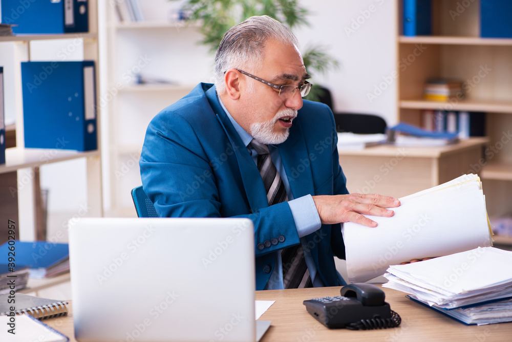 Old male bookkeeper unhappy with excessive work at workplace Old male bookkeeper unhappy with excessive work at workplace