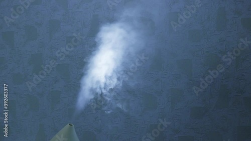 A fallow jet is emitted from the humidifier. An ultrasonic humidifier atomizes water vapor. Illuminated steam. photo