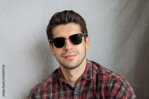 Portrait of a cool latin man in black sunglasses with a serious face expression looking in to the camera 