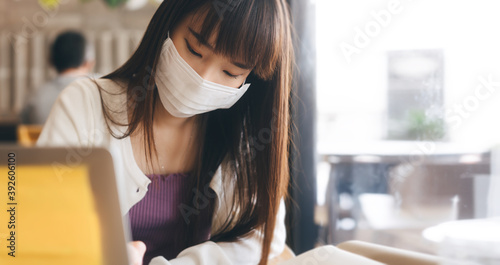 Young adult asian student female with face mask for virus corona or covid 19 study at cafe.