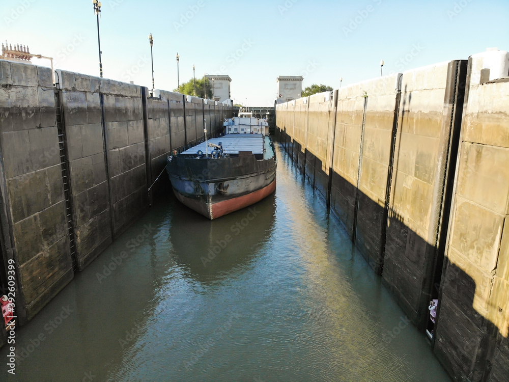 Fototapeta premium Cargo transportation by water transport. The dry cargo ship stands at the wall in the canal lock chamber when the lock gates are opened. Volga-Don Shipping Canal. Volgograd. Russia.