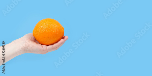 Hand holding organic delicious orange Isolated on blue Background. Healthy eating and dieting concept. Copy space. Free space for your text