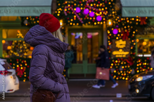 Christmas lights urban street view with woman in coat back to camera enjoy by festive decorations