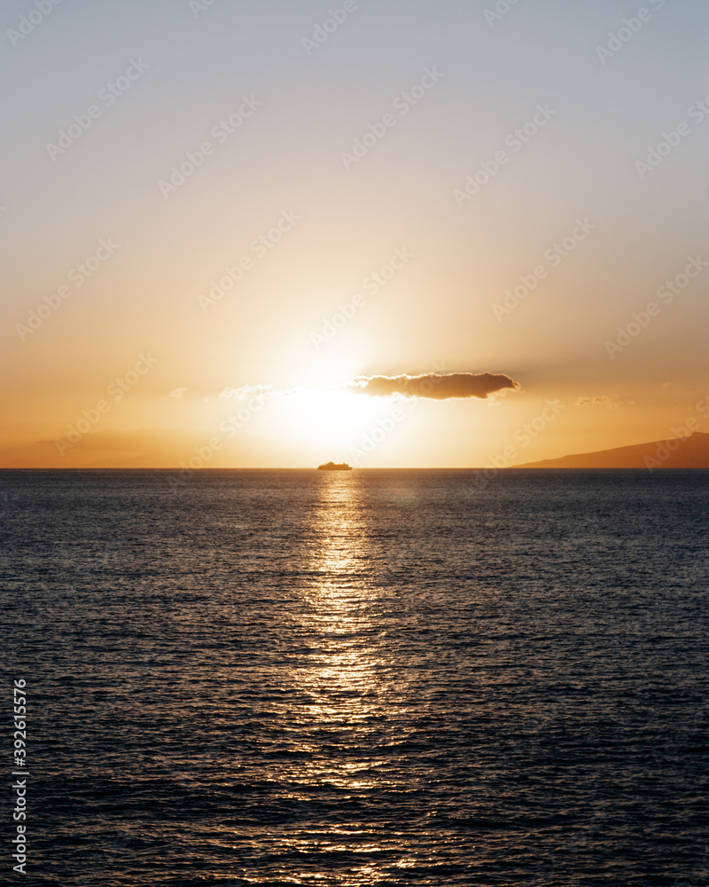 A sunset over the sea with a cruise ship in the middle of it