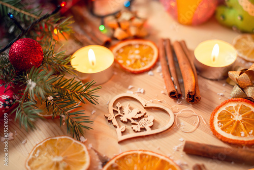 Self made wooden christmas tree decoration on wooden table with burning candles  sticks of cinnamon  dried slices of orange and branches of fir-tree. Festive atmosphere