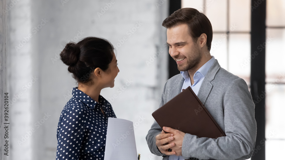 Thank you for advice. Pleasant smiling young indian woman corporate employee talking with caucasian male colleague at office hallway during short break discussing paperwork consulting sharing opinions Thank you for advice. Pleasant smiling young indian woman corporate employee talking with caucasian male colleague at office hallway during short break discussing paperwork consulting sharing opinions