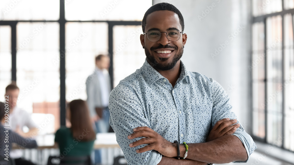 © fizkes - I made this. Portrait of ambitious confident black leader ceo standing with arms crossed on chest at office of successful profitable company looking at camera proud of his achievement career wellbeing