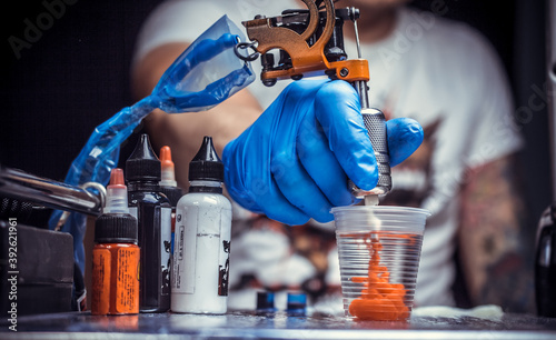Hand of a tattoo artist, holding a tattoo machine.
