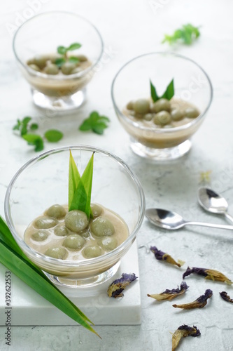 Shiny background for Kolak Putri Mandi or glutinous rice ball compote with pandan leaves  dried butterfly pea flowers and some mints. Selective focus
