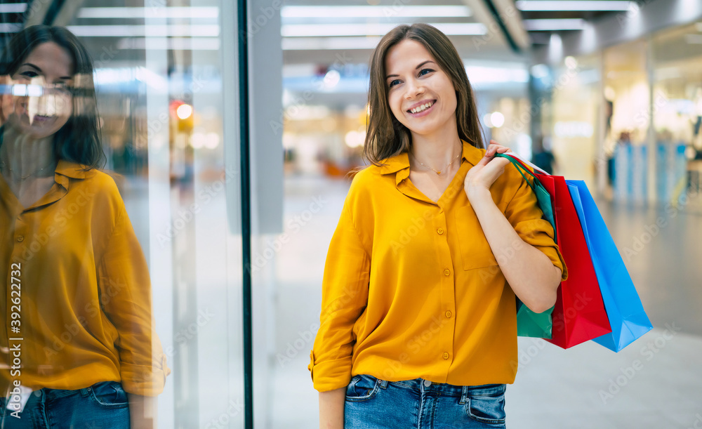 Cute modern woman is walking in the mall with shopping bags and having fun during black friday Cute modern woman is walking in the mall with shopping bags and having fun during black friday