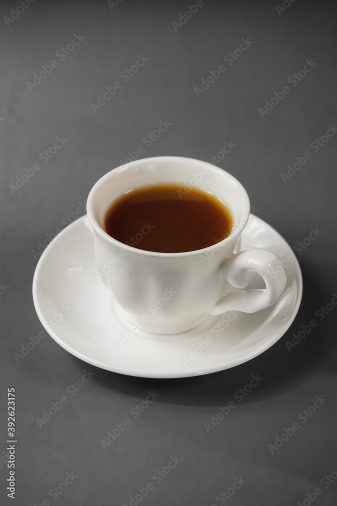Focus on a white cup of ginger tea in dark grey background Focus on a white cup of ginger tea in dark grey background
