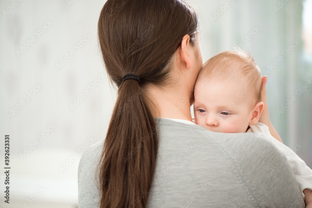 Young mother holding her newborn child. Mom nursing baby. Woman and new born boy relax in a white bedroom. Young mother holding her newborn child. Mom nursing baby. Woman and new born boy relax in a white bedroom.