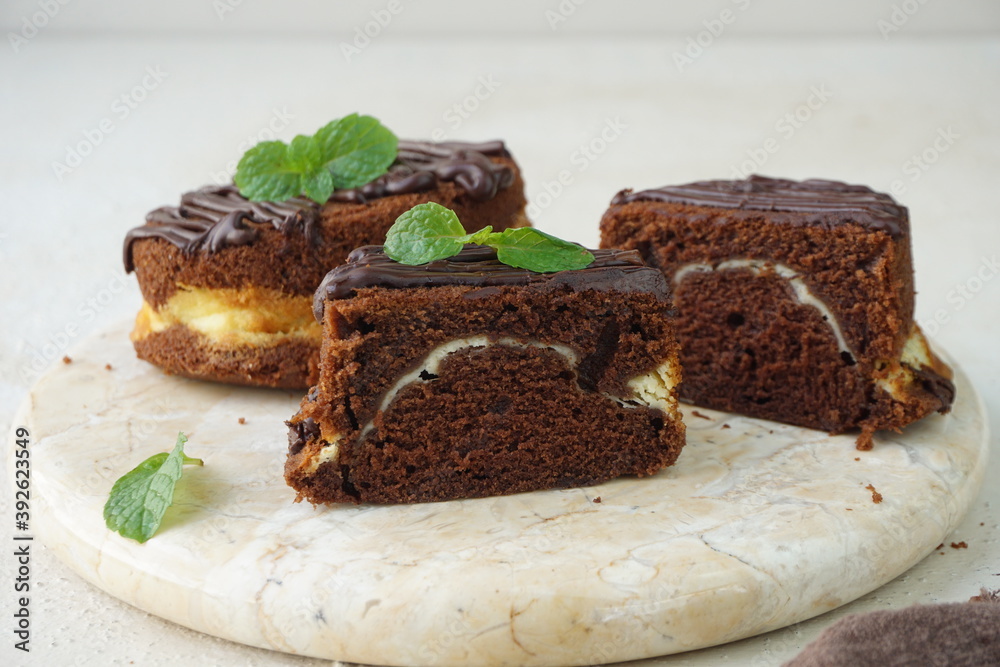 A view of slices heavenly chocolate cheese cake with mint leaves for garnish in marble board and grainy texture background A view of slices heavenly chocolate cheese cake with mint leaves for garnish in marble board and grainy texture background