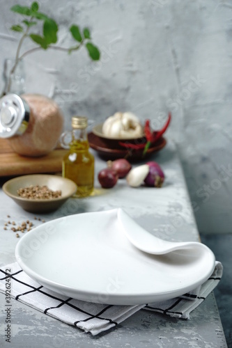 White empty ceramic plates with herb and spices as background. View of tableware for food preparation concept