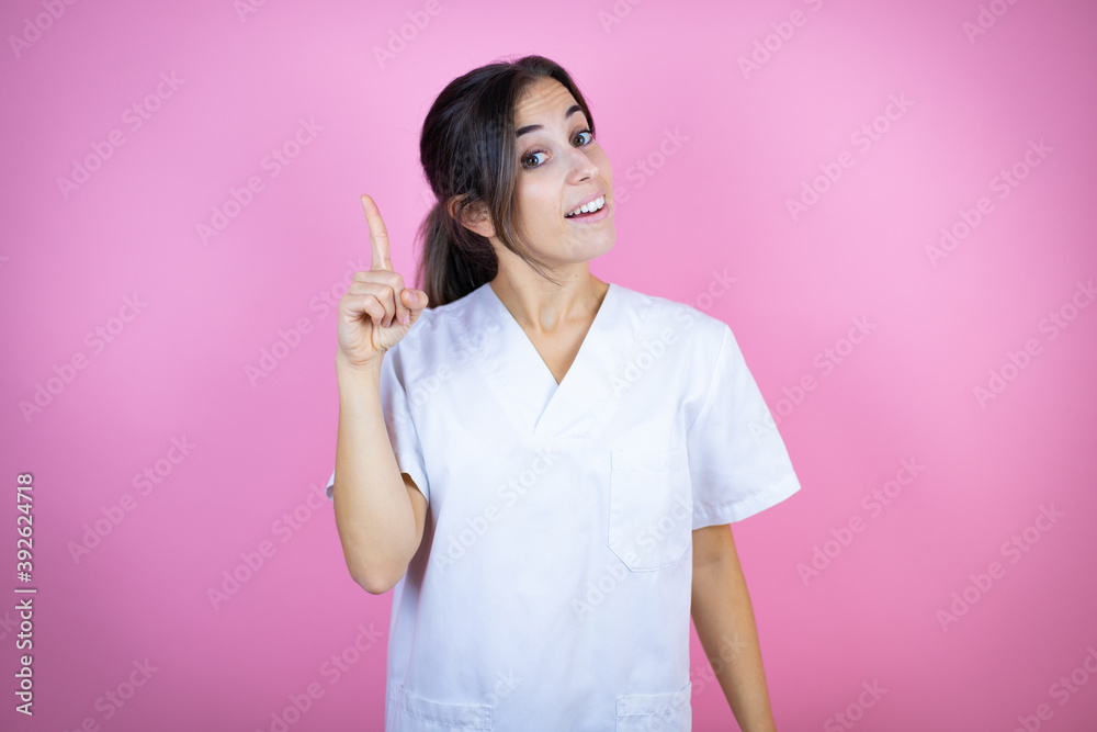 Young brunette doctor girl wearing nurse or surgeon uniform over isolated pink background surprised and thinking with her finger on her head that she has an idea.