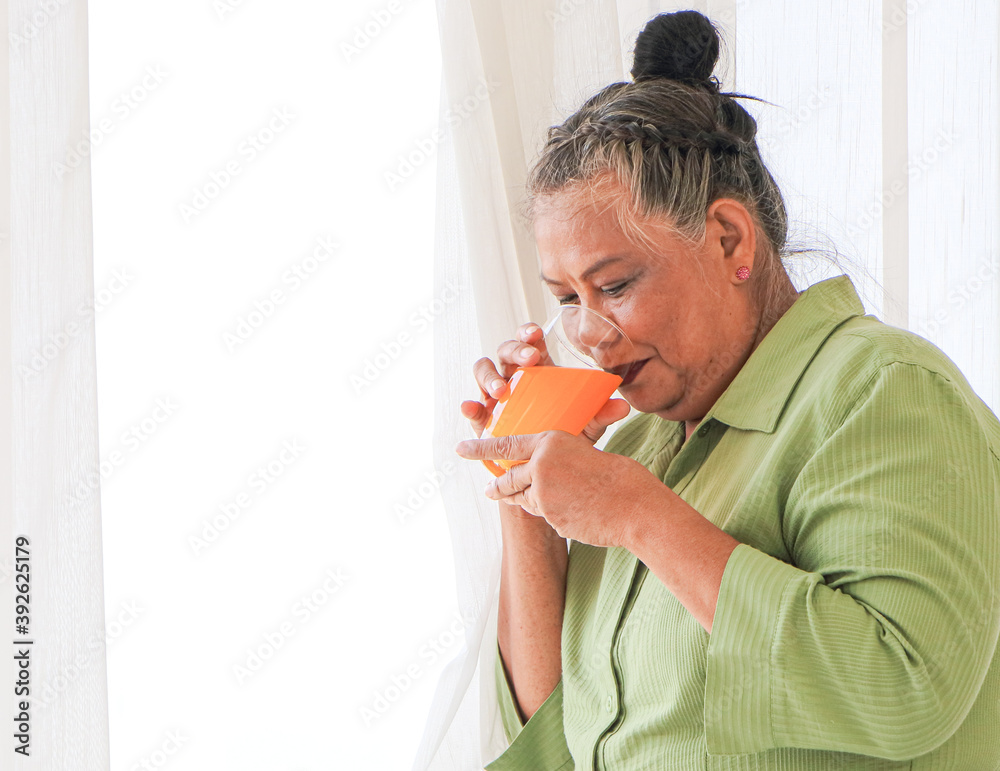Senior Asian women I was drinking orange juice while standing by the window in the background of the room. Senior Asian women I was drinking orange juice while standing by the window in the background of the room.