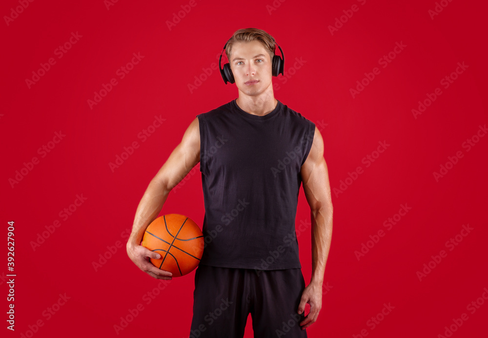 Attractive millennial basketball player listening to music, wearing  headphones over red studio background Stock Photo | Adobe Stock
