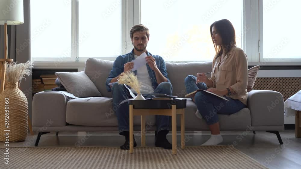 Frustrated young adult couple feeling stressed about high mortgage rates doing paperwork at home. Angry husband and wife renters calculating household payments, having financial problems or bank debt. Frustrated young adult couple feeling stressed about high mortgage rates doing paperwork at home. Angry husband and wife renters calculating household payments, having financial problems or bank debt.