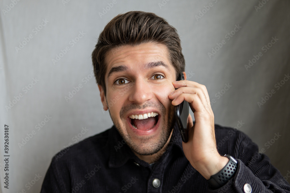 Portrait of a young cheerful man receiving a great news on his mobile phone with a happy expression on his face Portrait of a young cheerful man receiving a great news on his mobile phone with a happy expression on his face