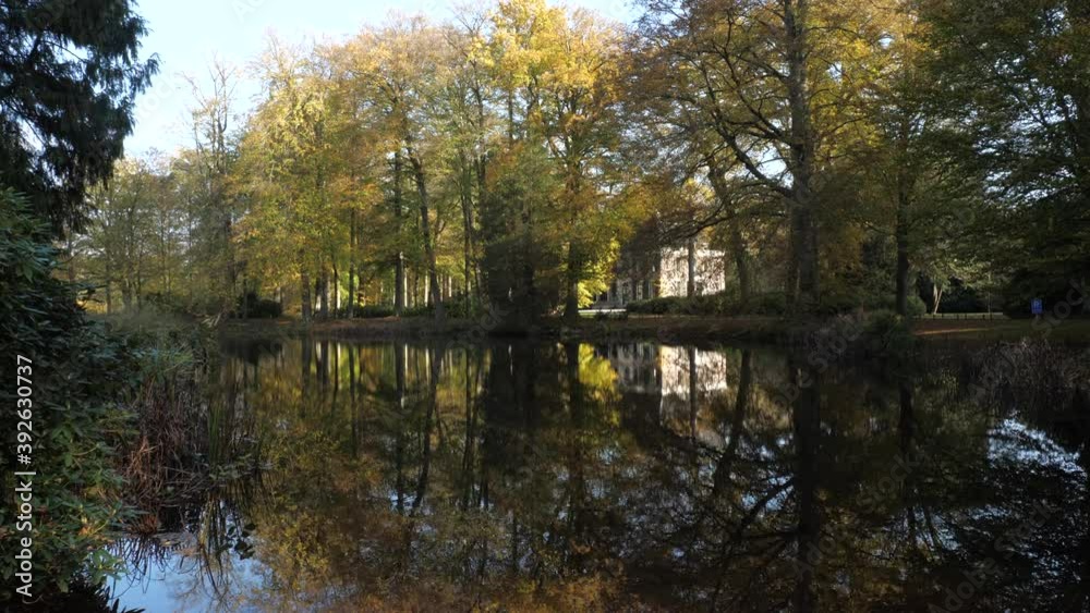 Big landhouse in Autumn forest with water reflections in lake Big landhouse in Autumn forest with water reflections in lake