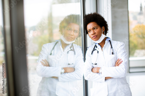 Black female doctor standing by the office window with negative expression