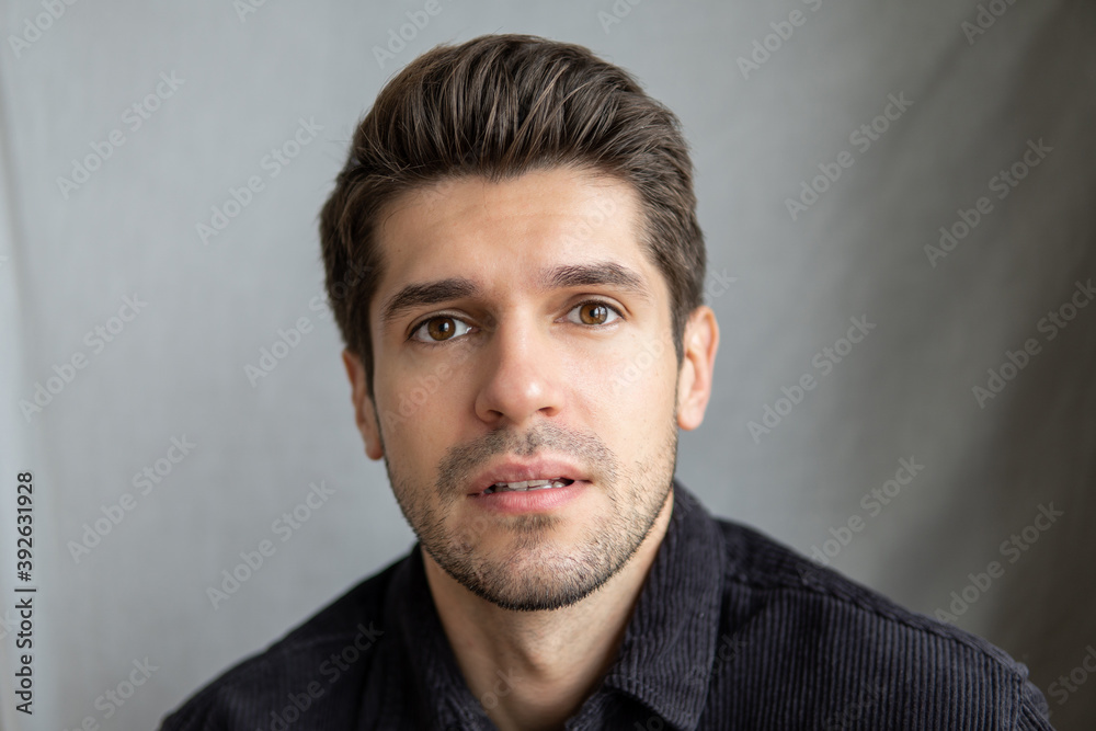 Portrait of a young beautiful man looking in to the camera with a slightly disappointed face expression Portrait of a young beautiful man looking in to the camera with a slightly disappointed face expression
