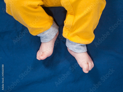 Baby legs in yellow pants. Bare feet photo