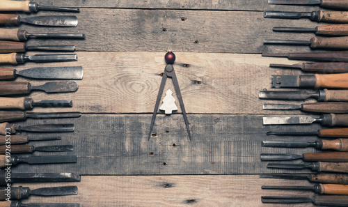 Photos Many firmer chisels as frame on a rustic workbench, steel compass as Christmas t