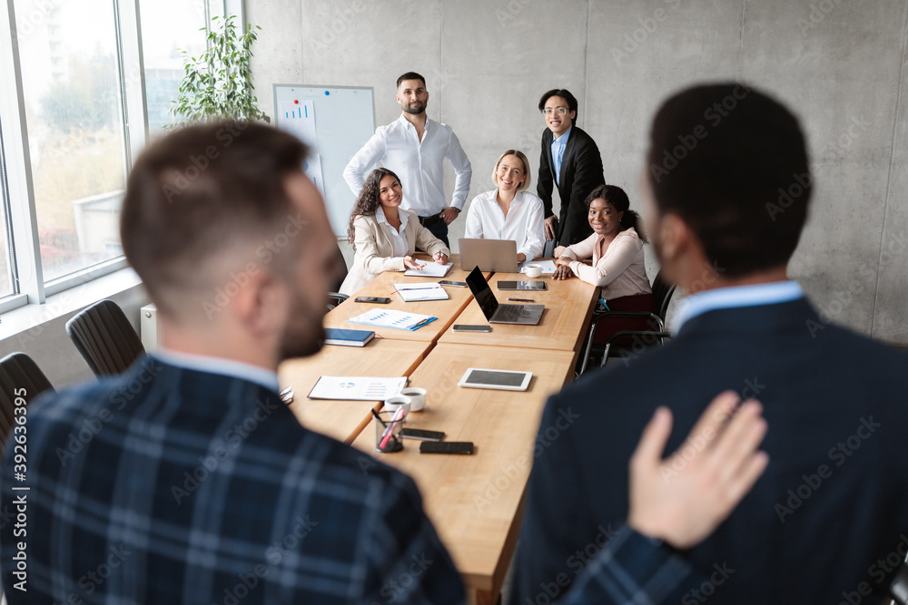 Businessman Introducing New Employee To Coworkers Standing In Office, Back-View