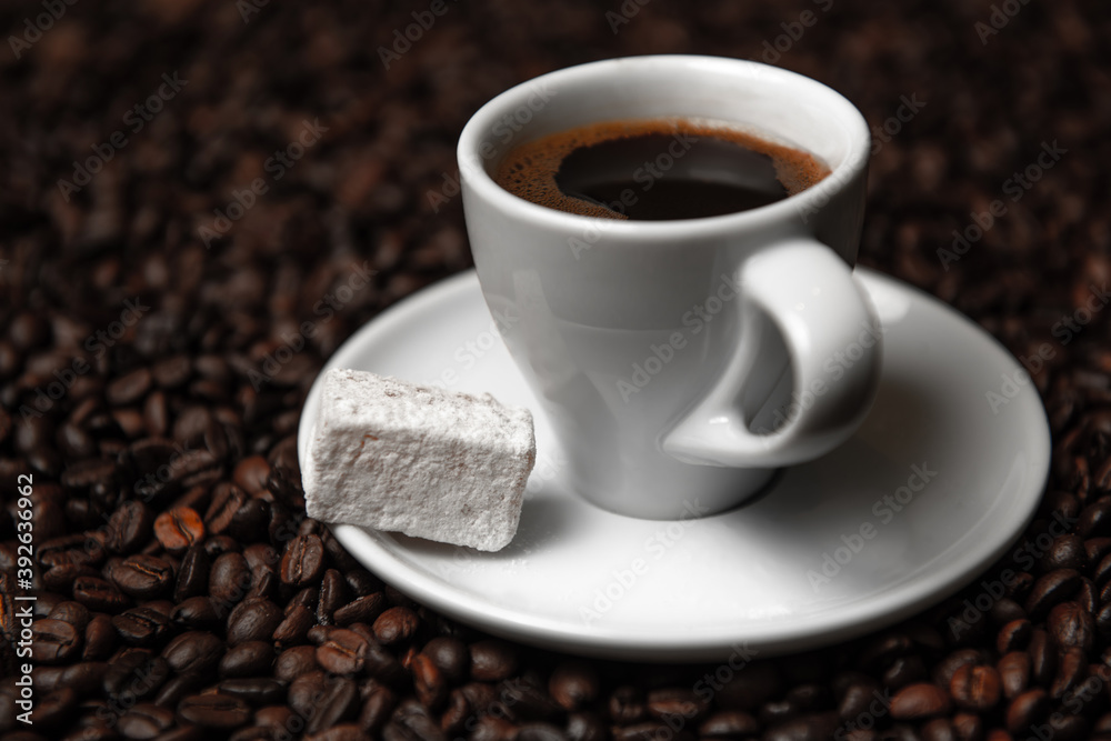 Hot coffee in white cup with Turkish delight on a saucer and coffee beans. Hot coffee in white cup with Turkish delight on a saucer and coffee beans.