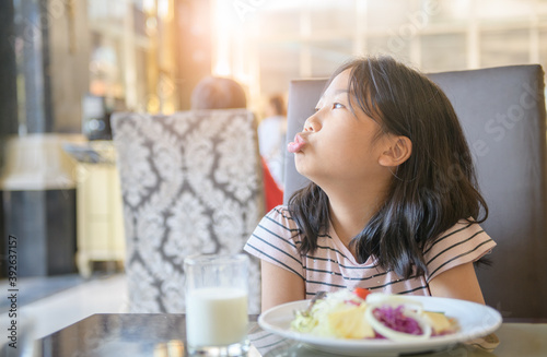 asian child girl with expression of disgust against vegetables in restaurant 