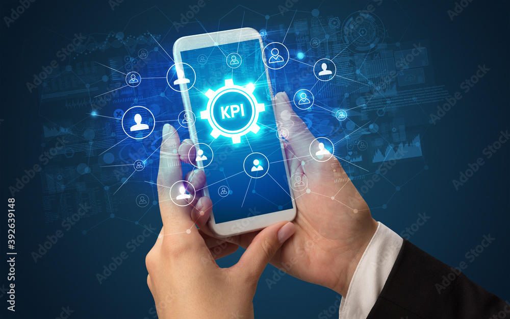 Female hand holding smartphone with KPI abbreviation, modern technology concept Female hand holding smartphone with KPI abbreviation, modern technology concept