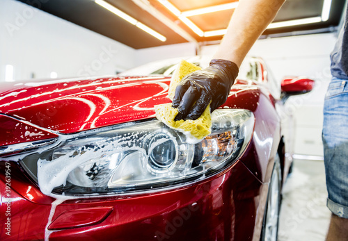Worker washing red car with sponge on a car wash © romaset