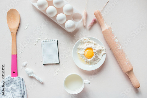 Ingredients for baking on a white, lilac background: eggs, flour, whisk, rolling pin. View from above. Copy space. workplace in the kitchen. Christmas kitchen atmosphere. Frame for cooking