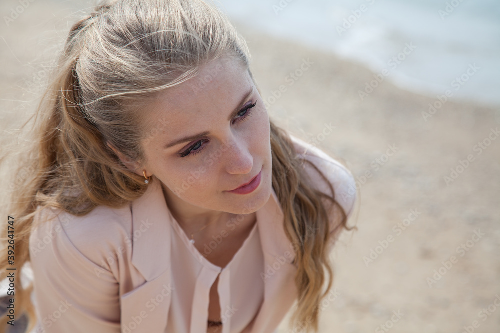 Beautiful blonde woman walks on an empty beach near the sea alone Beautiful blonde woman walks on an empty beach near the sea alone