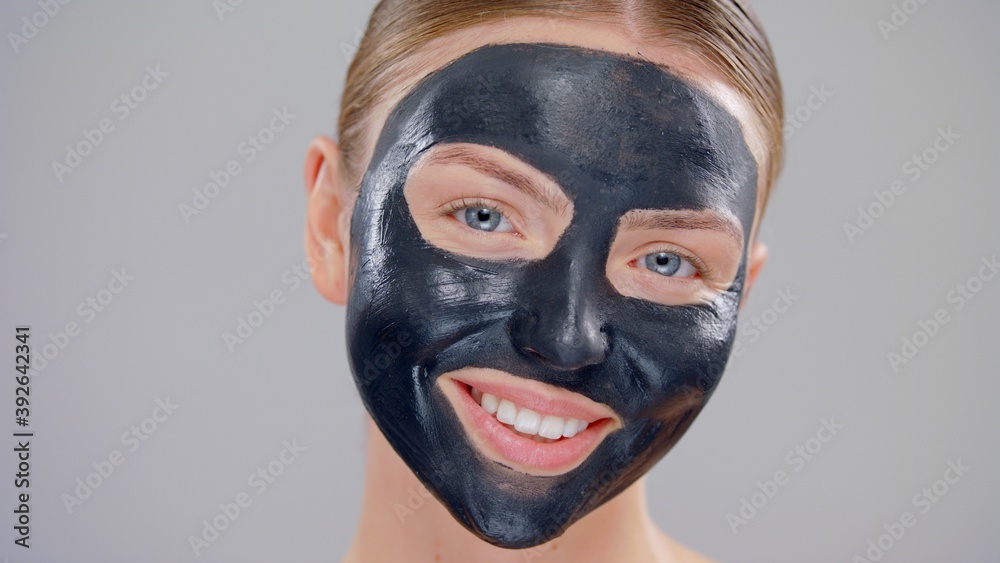 Clouse-up Portrait Young Caucasian Beautiful Blonde Woman With Blue Eyes And Black Mask Cosmetic On Face And Smiling On Gray Background Skin Care Concept Clouse-up Portrait Young Caucasian Beautiful Blonde Woman With Blue Eyes And Black Mask Cosmetic On Face And Smiling On Gray Background Skin Care Concept