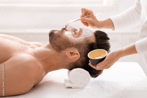 Bearded man getting face treatment at spa salon photo