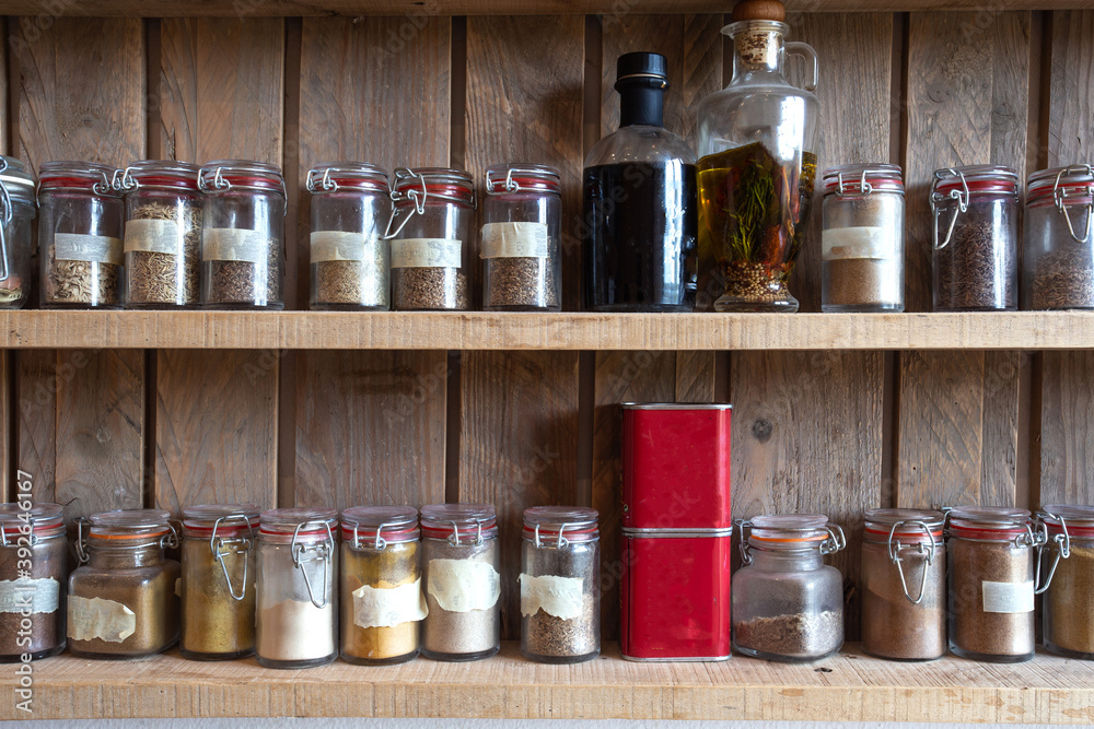 Bottles with spices and seasonings in wooden rack. Various different organic herbs for in the kitchen vintage look Bottles with spices and seasonings in wooden rack. Various different organic herbs for in the kitchen vintage look