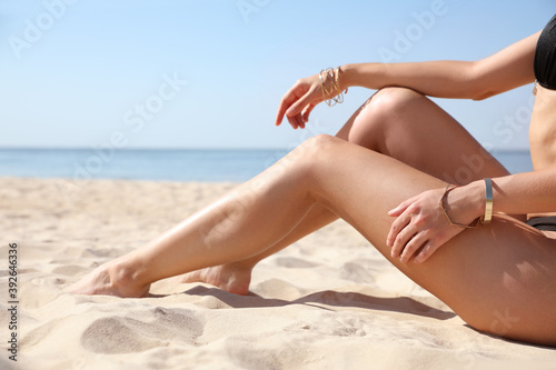 Young woman with beautiful body on sandy beach, closeup