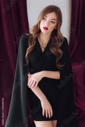 Portrait of beautiful young girl with makeup in black dress. Fashion photo